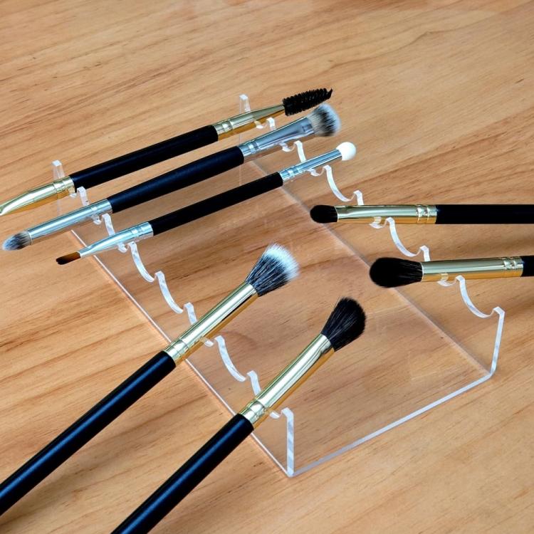 Clear acrylic makeup brush storage stand displaying several brushes in slots