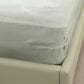 Installed gray anti-slip sheet clip securing sheet corner on a sofa
