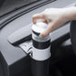 Car dashboard cup holder with black-and-white cylindrical cup holder; hand holding mug