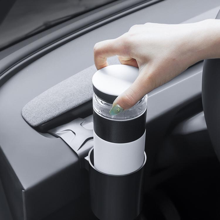 Car dashboard cup holder with black-and-white cylindrical cup holder; hand holding mug