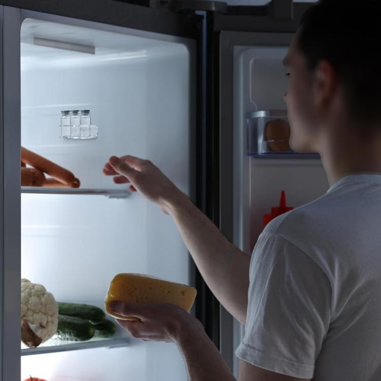Person reaching for bottles from an open fridge shelf with a three-hole stand