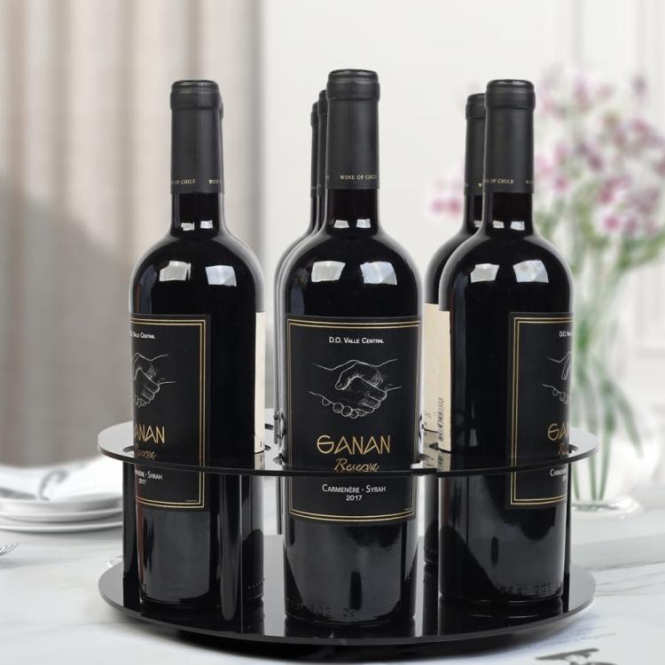 Black round acrylic bottle holder holding three dark wine bottles
