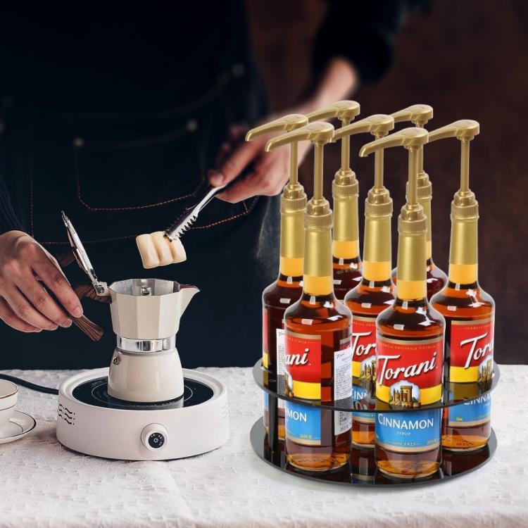 Black round acrylic bottle holder with syrup bottles and gold pump dispensers
