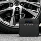 Black tire inflator resting near a car wheel, showing blue pressure readout