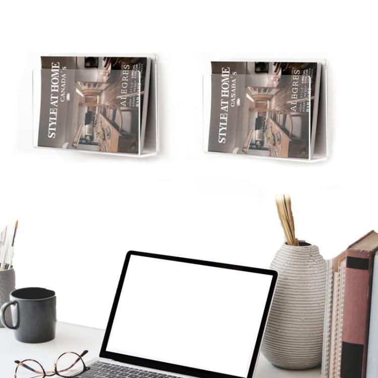 Wall-mounted clear acrylic magazine holders holding books above a seating area