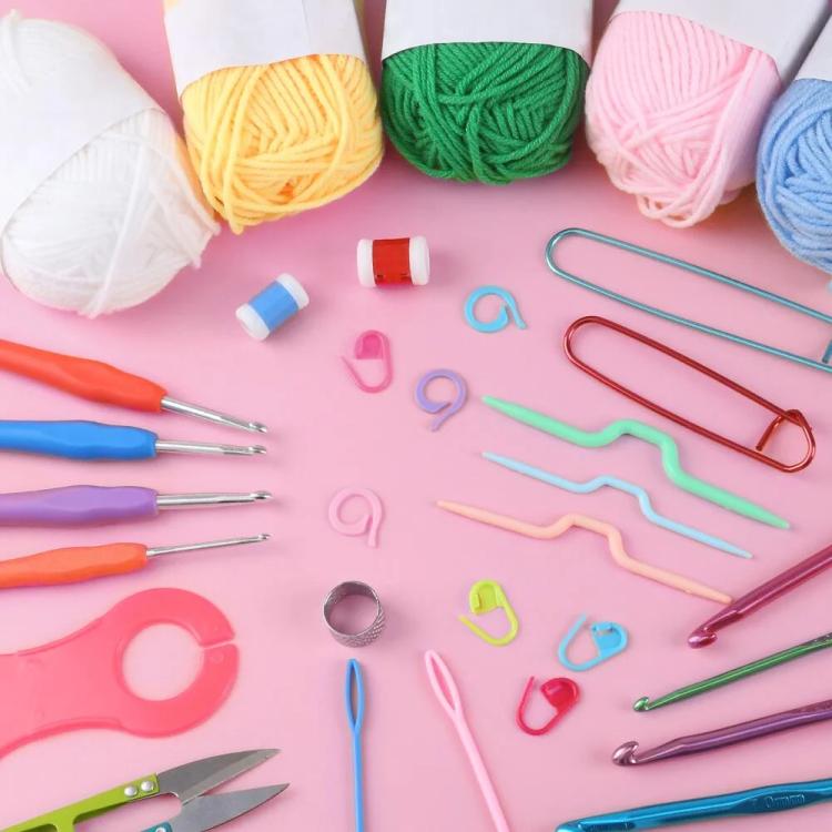 Crochet kit set with yarn balls and colorful crochet hooks on pink surface