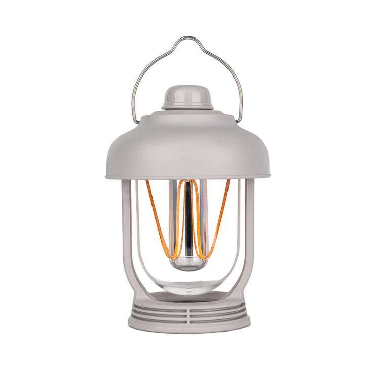 Light gray portable camping lantern with hanging handle and glowing filament bulbs