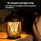 Black portable camping lantern with warm glowing filament bulbs inside clear glass