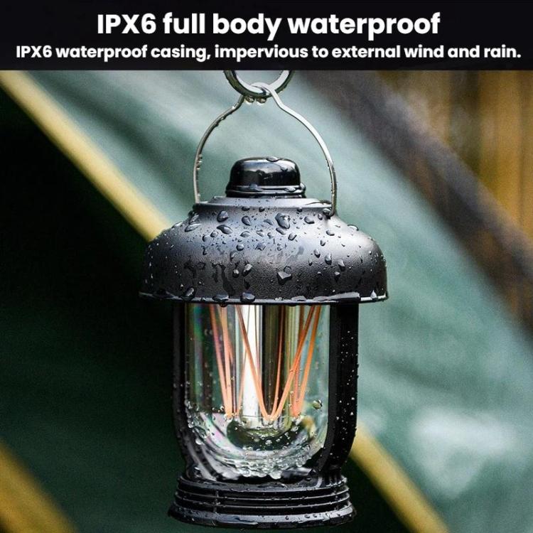 Black waterproof camping lantern with water droplets on glass and warm glowing bulbs