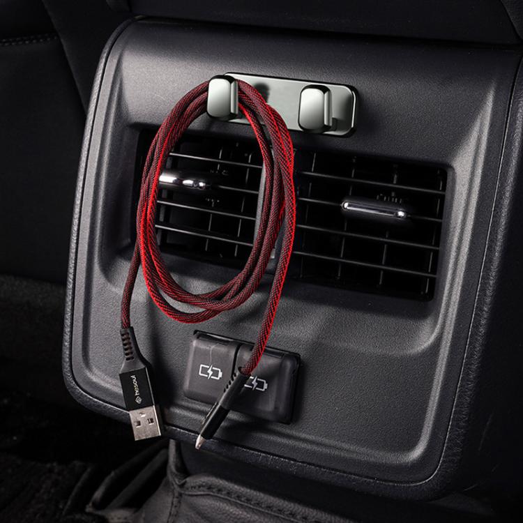 Light silver adhesive hooks installed near car air vent, holding lanyard cable