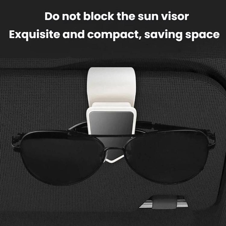 Car sun visor glasses clip holding black sunglasses, with white mounting strap.