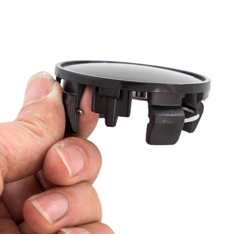 Black wheel center cap held in hand, showing side clip tabs