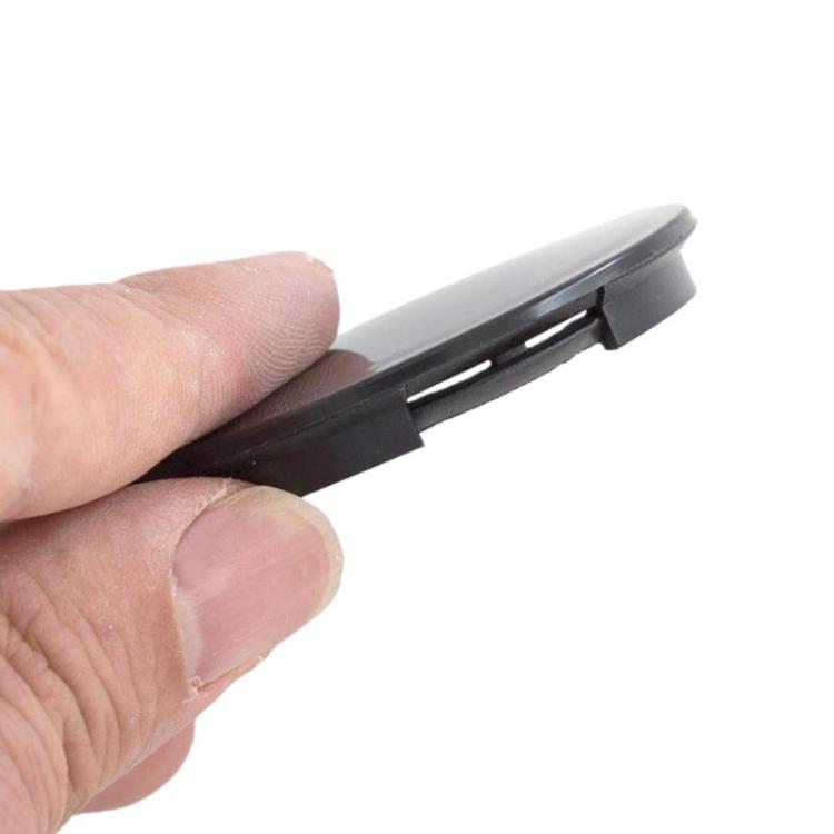 Black wheel center cap held by hand, showing side clips and fit tabs