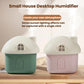 Pair of mini house desktop humidifiers in green and pink with white roofs, mist
