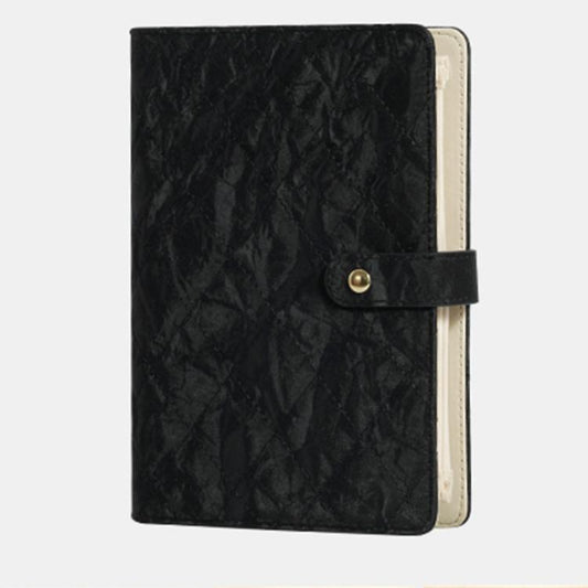 Black quilted jewelry organizer book with snap front strap and beige interior backing.