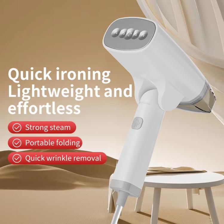 White handheld garment steamer steaming fabric on a table, compact foldable design