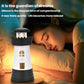 Dark gray lighthouse-shaped humidifier with illuminated windows on a nightstand