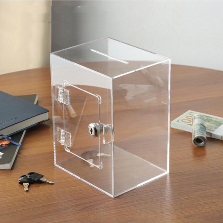 Clear acrylic money bank with metal lock and keys on tabletop, open viewing