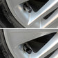 Close-up of black carbon-textured valve stem cap on a car wheel rim
