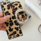 Leopard print fabric belt, close-up of silver oval buckle on tan strap