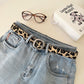 Leopard print belt with silver metal buckle on light-wash jeans