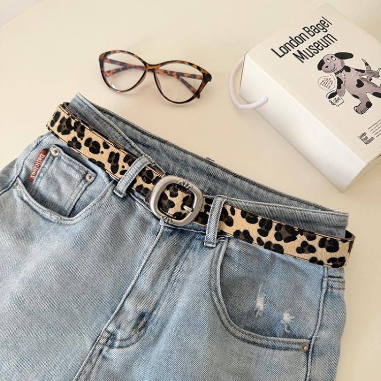 Leopard print belt with silver metal buckle on light-wash jeans