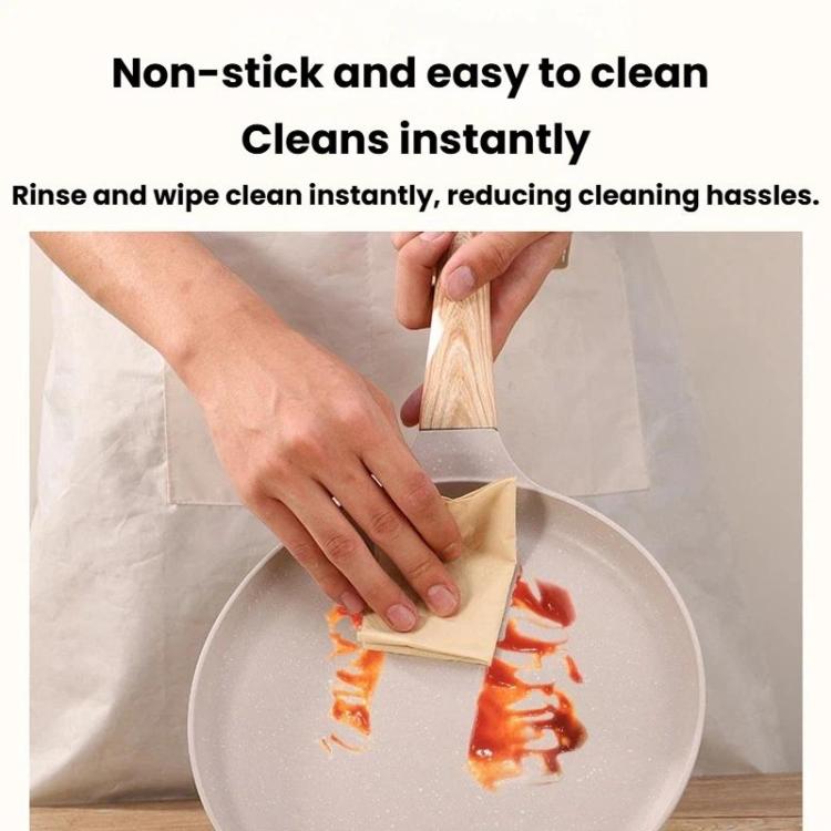 Beige nonstick frying pan being wiped clean with a paper towel
