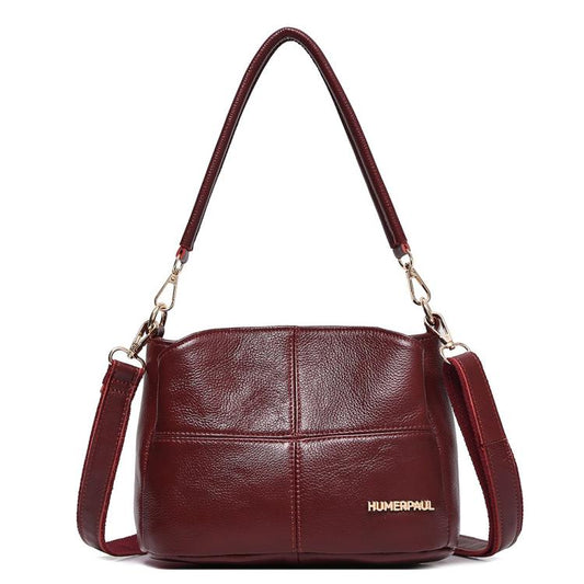 Red leather shoulder bag with top handles and crossbody strap, front logo patch