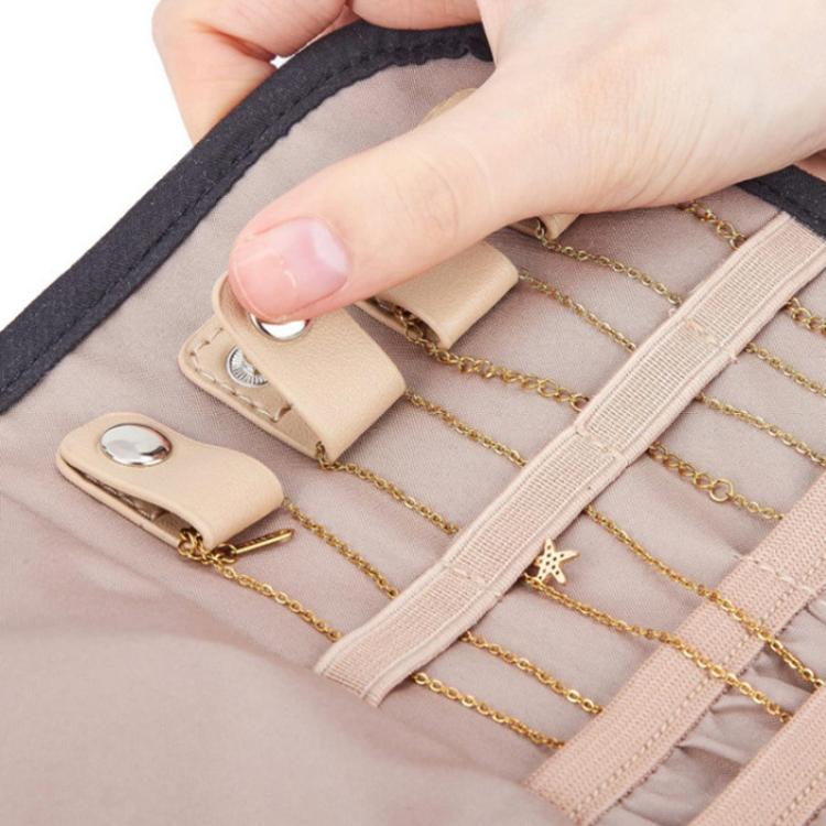 Pink faux-suede jewelry roll bag interior with elastic slots, hand adjusting dividers