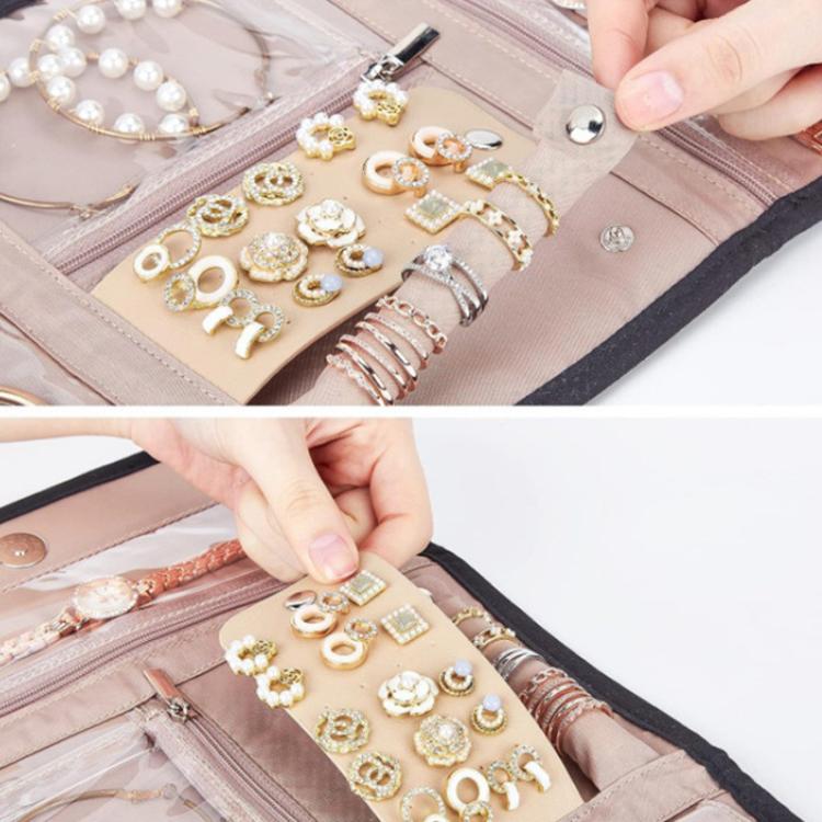 Pink faux-suede jewelry roll bag interior with ring and earring organizers, hands arranging