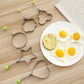 Five egg molds with handles and green knobs for shaping sunny-side eggs
