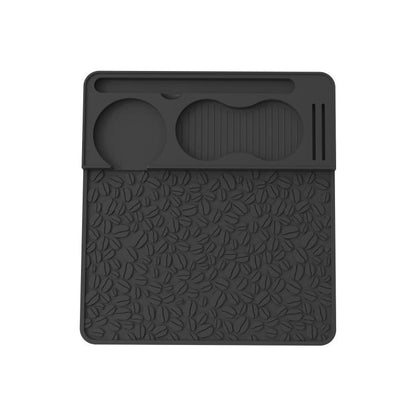 Black silicone espresso tamper mat with leaf-pattern texture and molded holder grooves