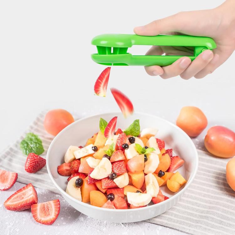 Green strawberry fruit slicer with handle and slicing arm, handheld tool