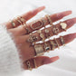 Assorted rose-gold tone heart and flower chain rings worn on hands, multiple styles