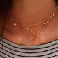Gold-tone layered star pendant necklace worn with small bead and star accents