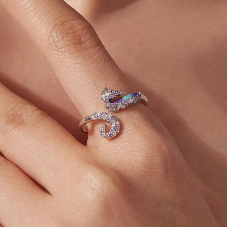 Close-up of adjustable seahorse opening ring on hand, silver tone with purple-blue stones