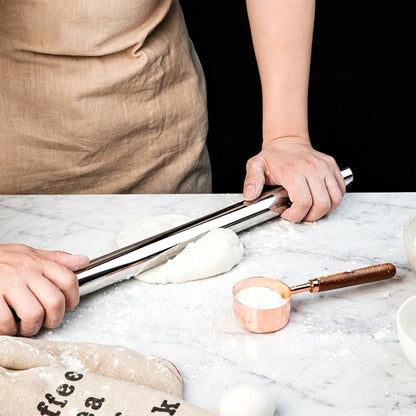 Stainless steel rolling pin with parallel rods, used to smooth dough on a countertop