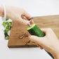 Hands rotating spiral cucumber slicer to cut cucumber spirals on a board