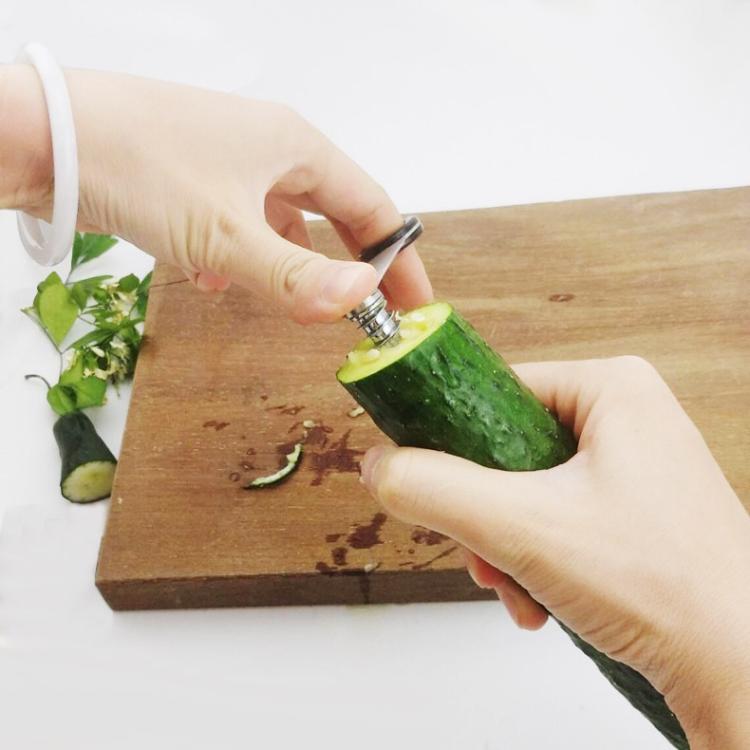Hands rotating spiral cucumber slicer to cut cucumber spirals on a board