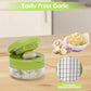 Green manual garlic press open on board, garlic cloves and crushed garlic in clear bowl.