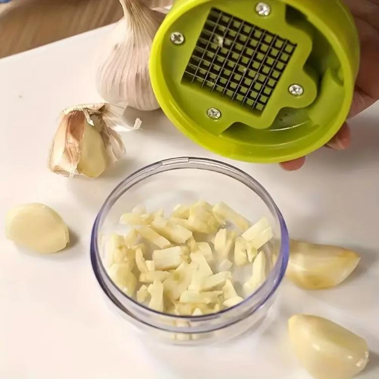 Green manual garlic press grating plate over a bowl of chopped garlic pieces.