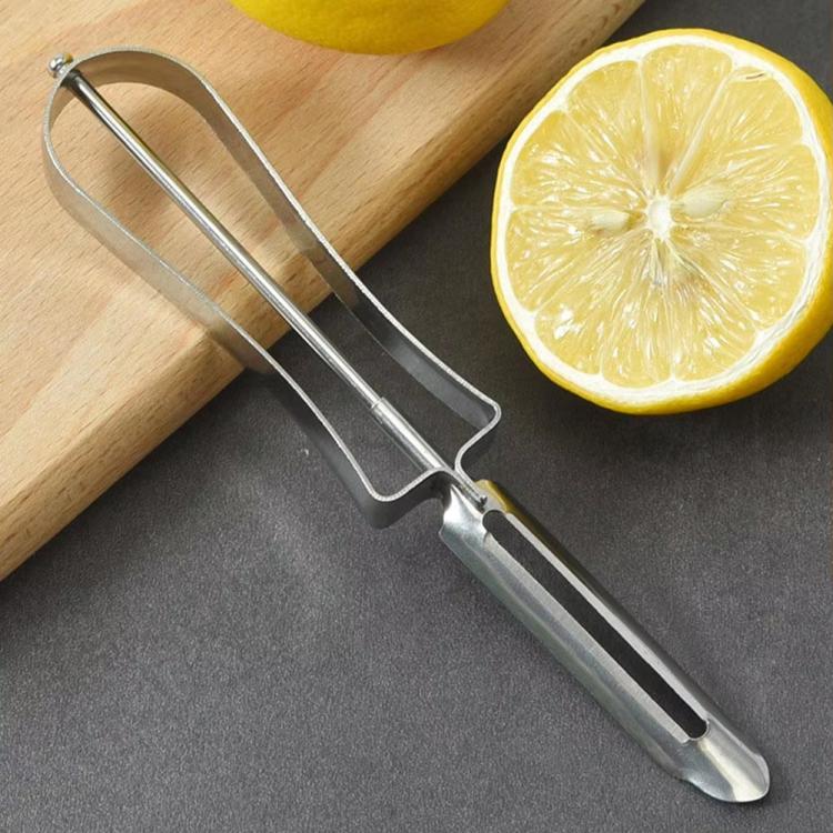 Stainless steel vegetable peeler with curved handle, beside lemon on board.