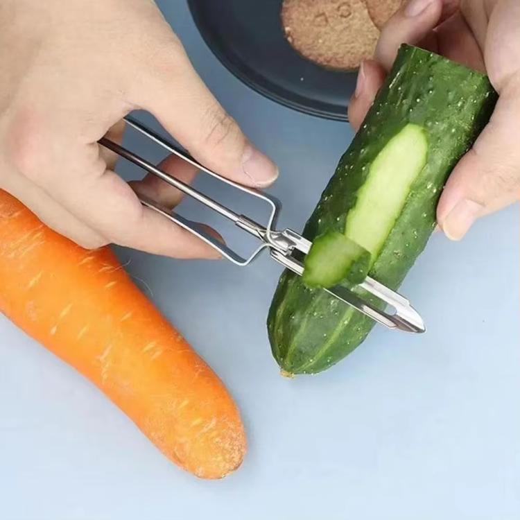 Vegetable peeler cutting wide peels from zucchini and carrot on a tray.