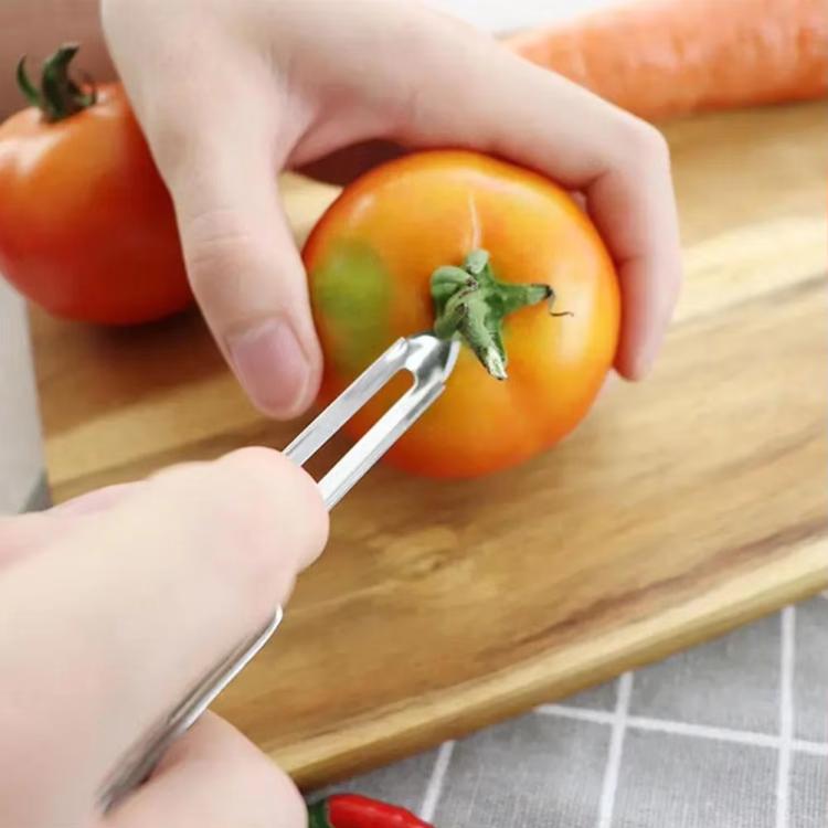 Fruit peeler removing peel from an orange, stainless blade near fruit surface.