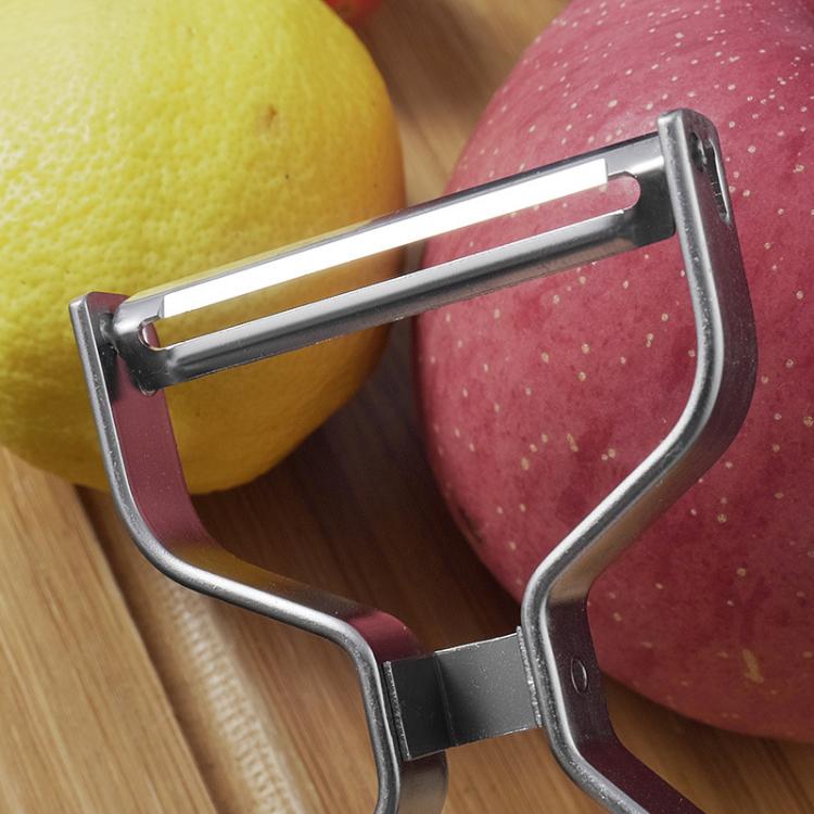 Stainless steel peeler cutter frame close-up, positioned on cut fruit