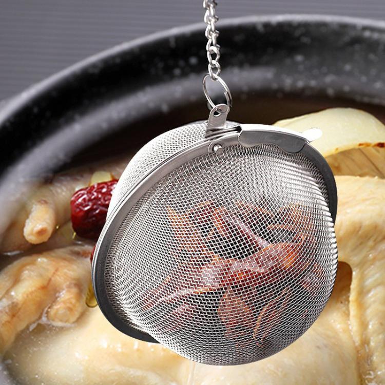 Stainless steel mesh tea infuser ball with chain and clasp, suspended over cup
