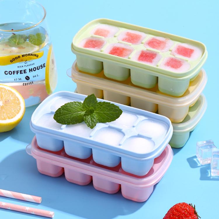 Stacked ice cube mold trays in light green and pink with fruit-flavored cube inserts