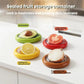 Four sealed fruit storage containers with silicone film seals, showing produce inside
