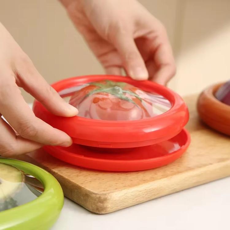 Red mini fruit storage container with silicone film seal, being closed by hands