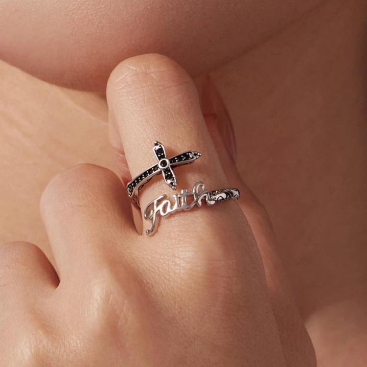 Close-up of adjustable cross ring on finger, black stone accents and Faith script